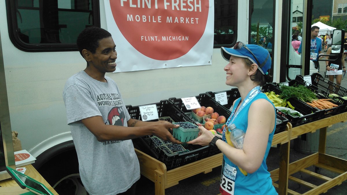 A runner purchases produce from the Flint Fresh Mobile Market (Community Foundation of Greater Flint)