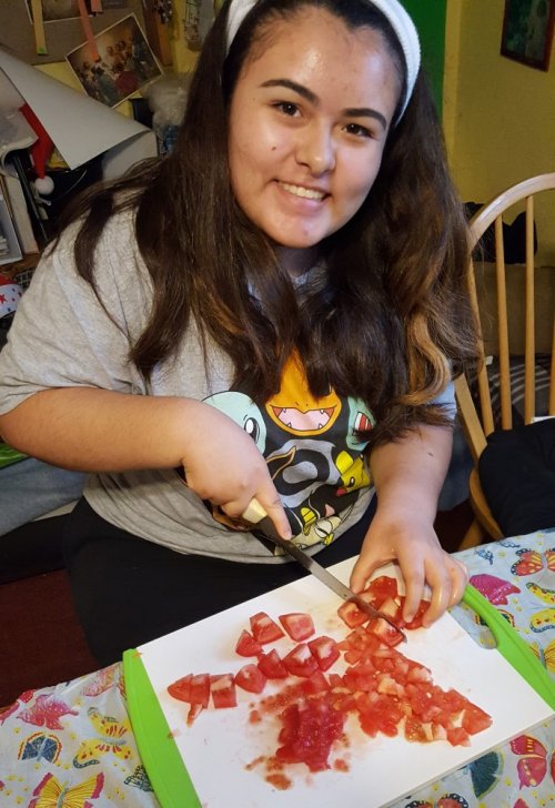 A teen participant in the Food as Medicine program chopping tomatoes for a mango salad. (University of California San Francisco Benioff Children’s Hospital)